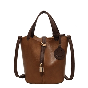 Vintage brown leather bucket bag with gold padlock and a cute round smiley face pendant