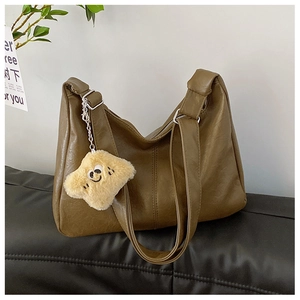 Close-up of olive green faux leather tote bag with a yellow plush smiley face pendant