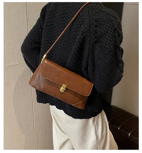 Détail d'un sac à épaule en cuir marron avec boucle dorée et texture travaillée