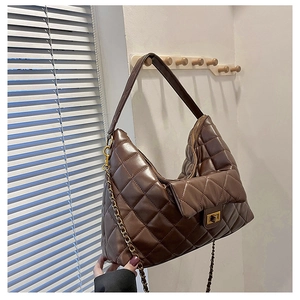 Detailed view of brown quilted tote bag featuring golden twist lock and metal chain strap