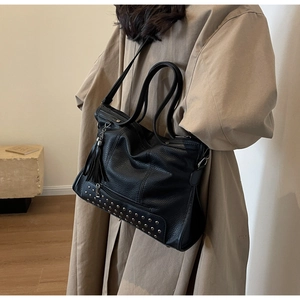 Detail of black pebbled leather tote featuring silver rivets and a stylish tassel charm