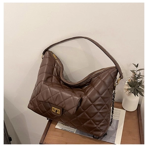 Detail of a brown quilted tote bag featuring a gold twist lock and chain strap