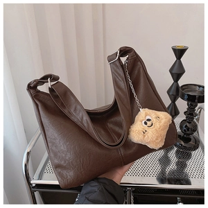Detail of dark brown leather tote bag with star plush charm and silver chain strap
