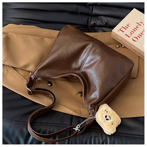 Detail of dark brown tote bag with retro pleated texture and yellow plush bear charm