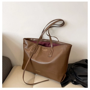 Close-up of brown embossed tote bag featuring crocodile pattern and golden logo