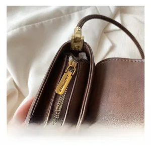 Détail de la fermeture éclair en métal gravée sur un sac à bandoulière marron vintage
