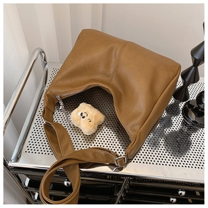 Detail of brown faux leather tote with silver zipper and yellow star plush charm