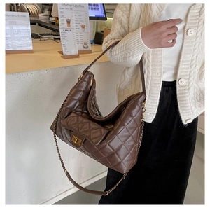 Macro detail of brown quilted leather texture and golden twist-lock on hobo tote bag