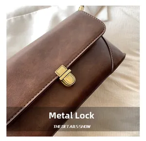 Gros plan du fermoir en métal sur un sac à bandoulière en cuir marron au style rétro