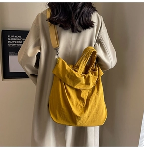 Detail einer großen gelben Nylon-Schultertasche mit Falten-Struktur und breitem Gurt