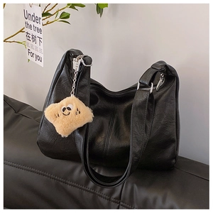 Detail of vintage wrinkled texture black tote bag with plush biscuit charm and zipper