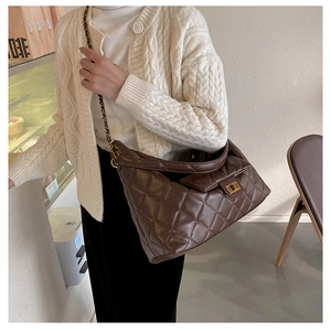 Detail of dark brown quilted leather hobo bag with gold chain strap and metal clasp