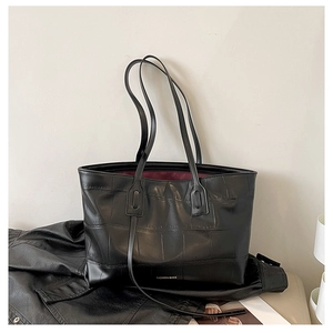 Detail view of black crocodile pattern tote bag with polished finish and logo