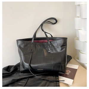 Detail of black crocodile texture tote bag with deep red lining and fashion logo