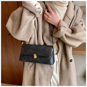 Détail d'un sac à bandoulière en cuir mat noir avec fermoir doré et fine bandoulière