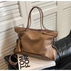 Detail of tan lychee grain leather tote bag with silver studs and leather tassel charm