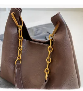 Détail d'un sac porté épaule en cuir marron avec chaîne dorée épaisse et brillante