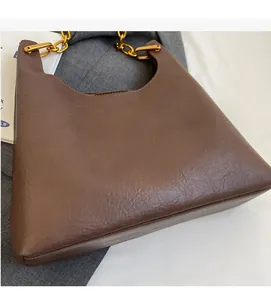 Détail du sac cabas marron foncé en cuir plissé vintage avec une chaîne en métal doré