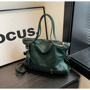 Detailed macro view of dark green leather tote with silver rivets and tassel detail