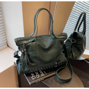 Detail of dark green lychee leather tote bag with metallic studs and fringe charm
