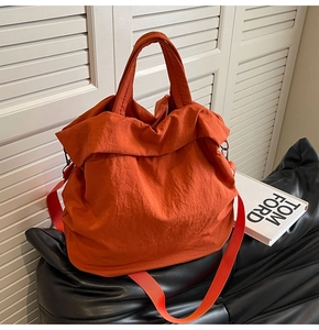 Detail einer leuchtend orangefarbenen Nylon-Beuteltasche mit Griff und Schultergurt