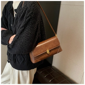 Détail du sac à bandoulière en cuir marron avec fermoir doré et coutures apparentes