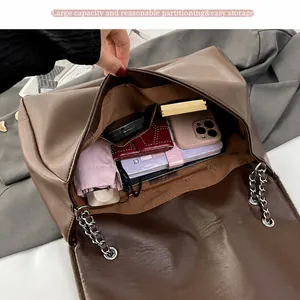 Vista detallada del espacioso interior del bolso tote de cuero marrón con asa de cadena