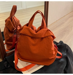 Detail einer leuchtend orangefarbenen Nylon-Beuteltasche mit verstellbaren Riemen und Textur