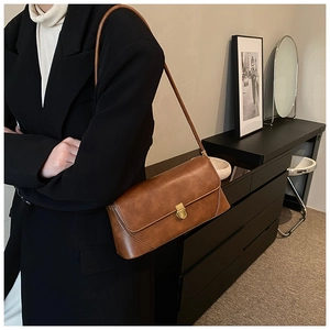 Détail du sac sous l'aisselle en cuir marron vintage avec boucle dorée sur costume
