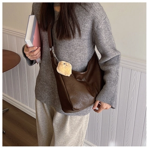 Detail of dark brown leather tote bag with silver hardware and yellow plush bear charm