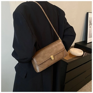 Détail d'un sac sous les aisselles en cuir marron vintage avec boucle dorée sur modèle