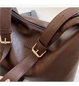Gros plan sur la texture du cuir marron avec détails métalliques dorés et bandoulière