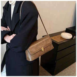 Détail du sac vintage marron montrant la texture du cuir et le fermoir doré poli