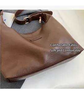Gros plan du sac hobo marron montrant le grain du cuir et le logo en relief