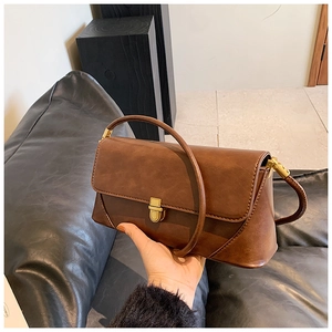 Détail d'un sac à main marron vintage avec fermoir doré sécurisé et texture en cuir