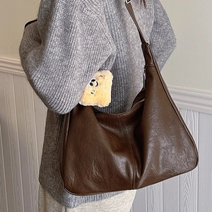 Brown faux leather tote bag with lychee texture and plush bear charm on grey sweater