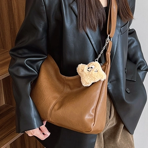 Brown leather hobo tote bag with plush star charm shown on model in retro urban outfit