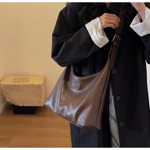 Détail d'un sac hobo marron foncé avec texture en cuir et étiquette BANATU