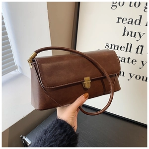 Détail d'un sac à main vintage en cuir marron avec fermoir doré et bandoulière texture