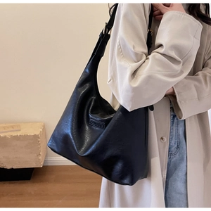 Détail du sac hobo en cuir noir avec texture fine et logo rectangulaire gaufré