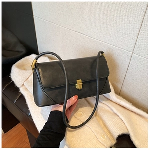 Détail d'un sac sous les bras vintage noir avec un fermoir en métal bronze rectangulaire