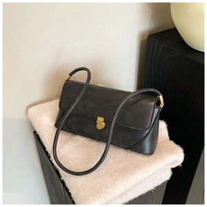 Détail du sac sous le bras noir minimaliste avec texture mate et boucle dorée élégante