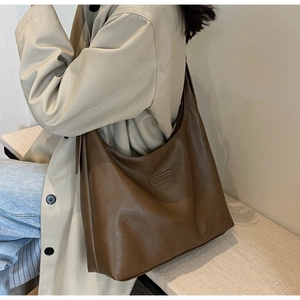 Vue détaillée d'un grand sac cabas vintage marron porté par un mannequin en décor minimaliste