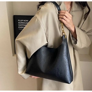 Détail du sac seau vintage noir avec chaîne dorée et texture plissée naturelle chic