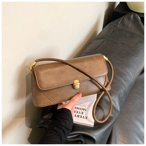 Gros plan sur un sac porté épaule marron rétro avec un fermoir en métal doré sophistiqué