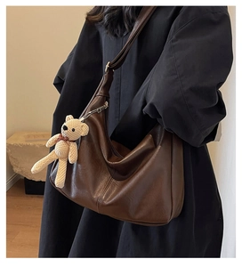 Detalle de bolso hobo suave marrón oscuro con un lindo colgante de oso para el diario