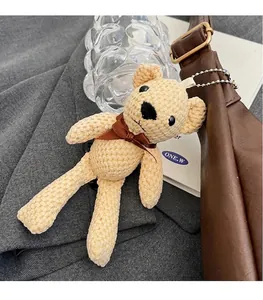 Primer plano del colgante de oso de punto beige en un bolso tote de cuero marrón