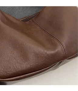 Detalle del bolso tote marrón oscuro con textura de cuero arrugado y costuras finas
