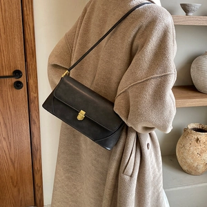Grand sac sous l'aisselle noir rétro présenté avec un manteau en laine beige femme
