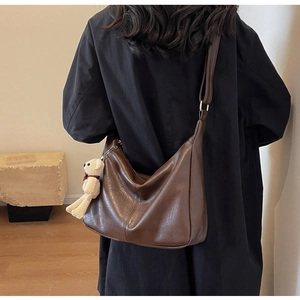 Detalle de bolso tote vintage marrón grande con colgante de osito de punto blanco